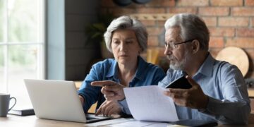 Picture of two people of retirement age on laptops and comparing options.