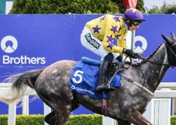 A jockey riding a horse with Close Brothers branding in the background