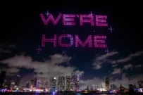 Night sky with "We're Home" illuminated in pink lights