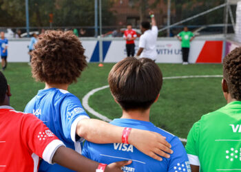 Kids with Visa branded football shirts stood on football pitch