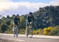 Two people cycling on with mountains